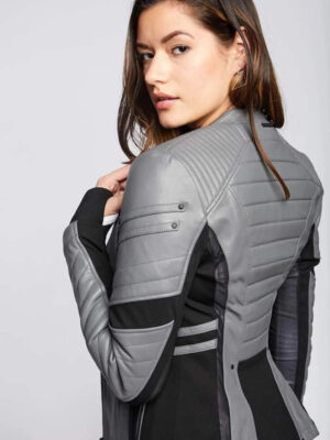 Close-up of woman turning back while wearing a grey and black leather jacket with padded design and triangular earrings.